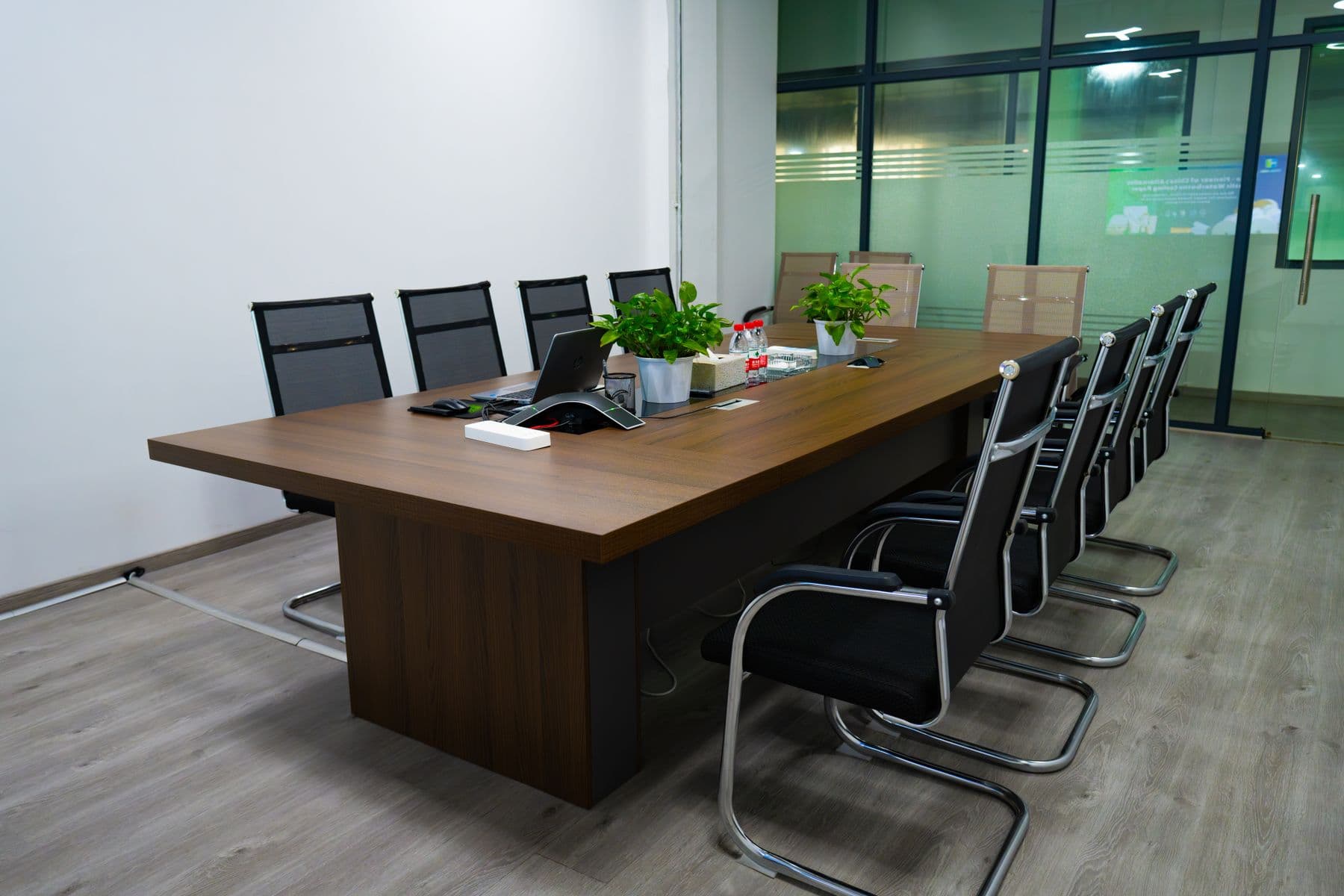 A dark timber boardroom table with leather chairs in an empty meeting room.