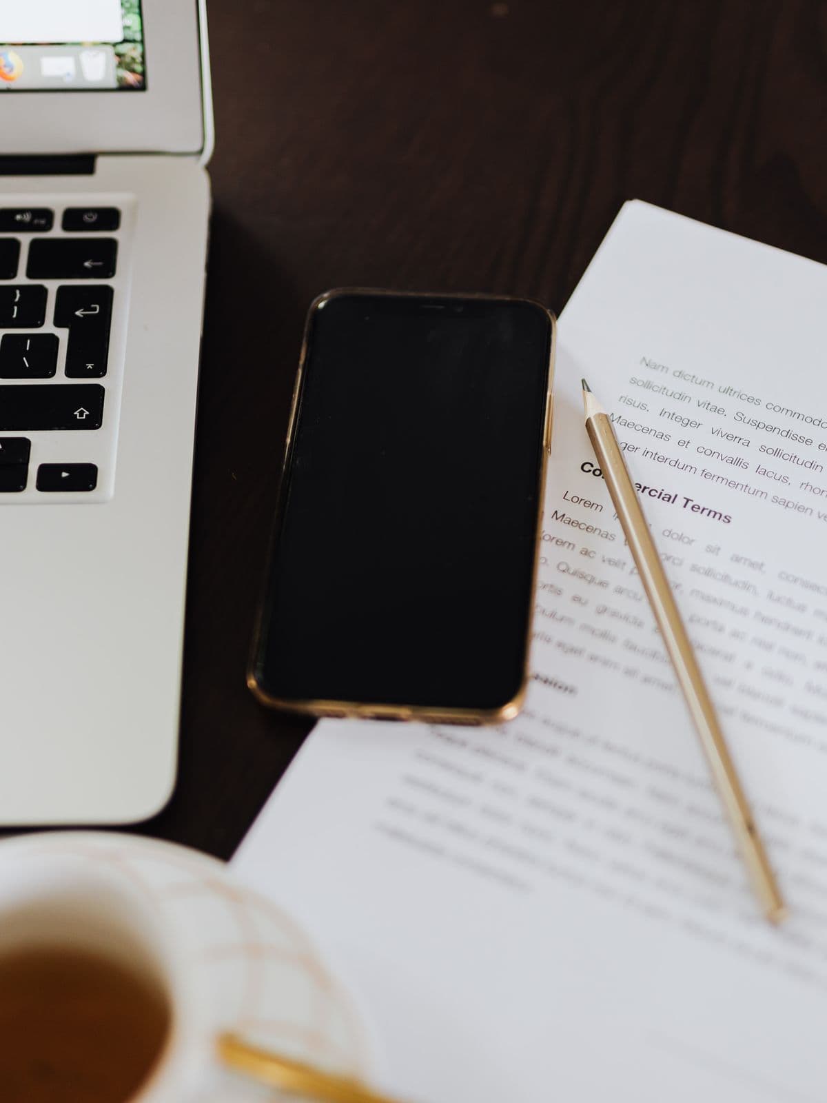 A commercial agreement on a desk beside a laptop, phone and pencil.