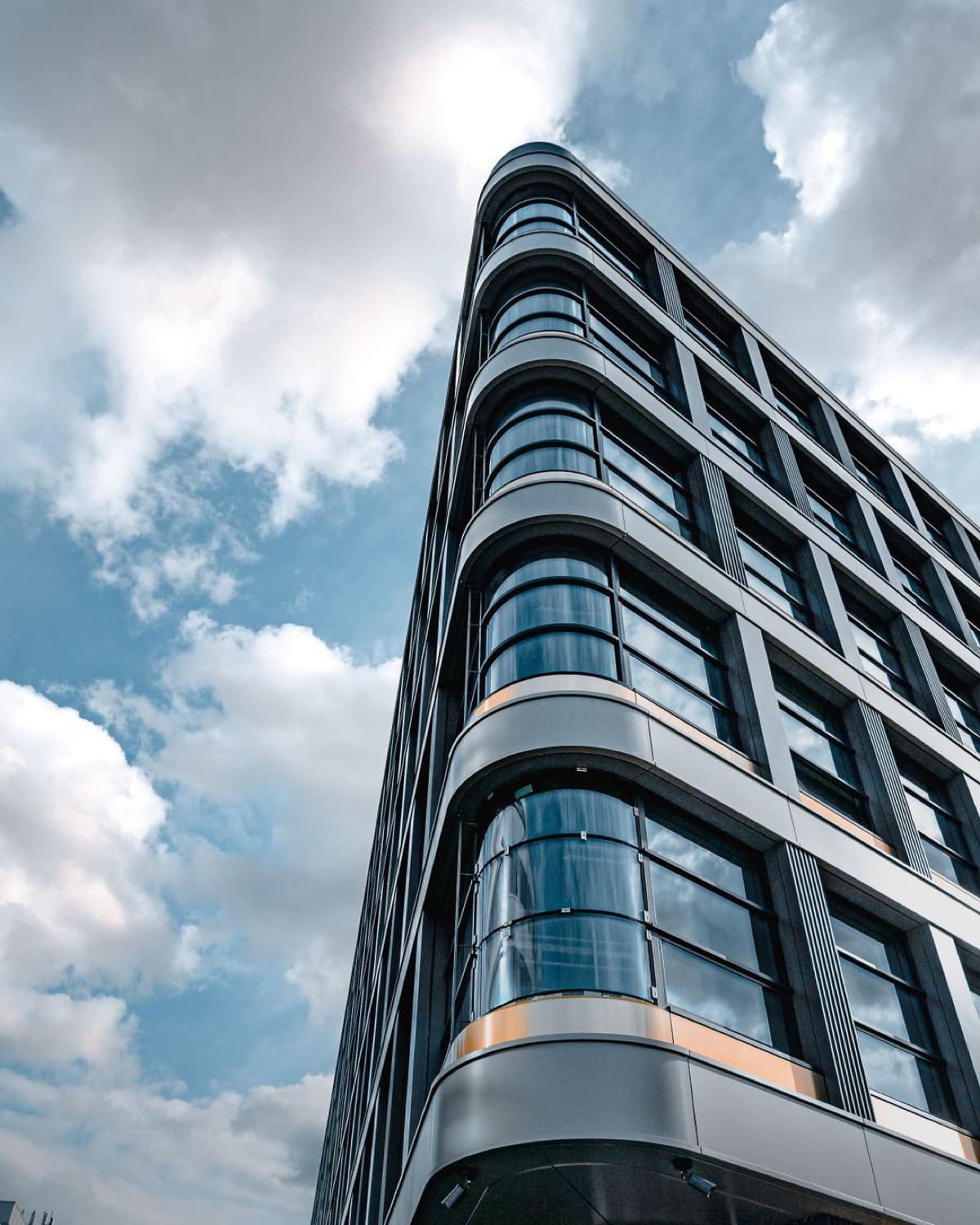 A modern glass office tower photographed from street level, looking up.